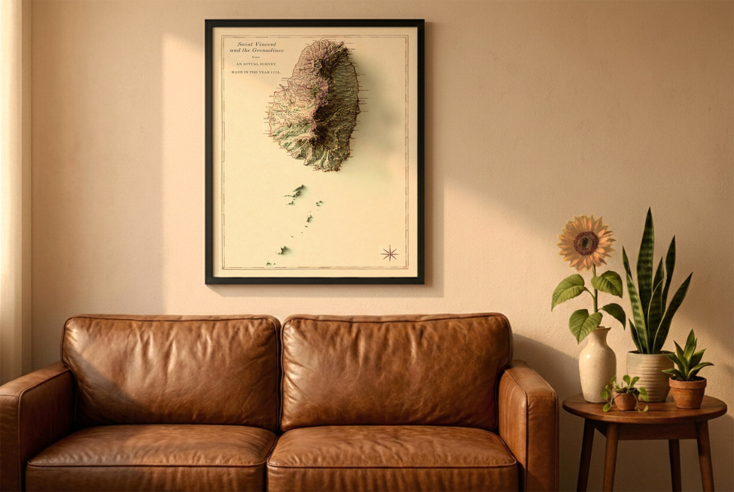 Saint Vincent and the Grenadines vintage relief map in a black frame above a brown leather sofa. Boho living room with warm sunlight, sunflower, and indoor plants on a wooden side table