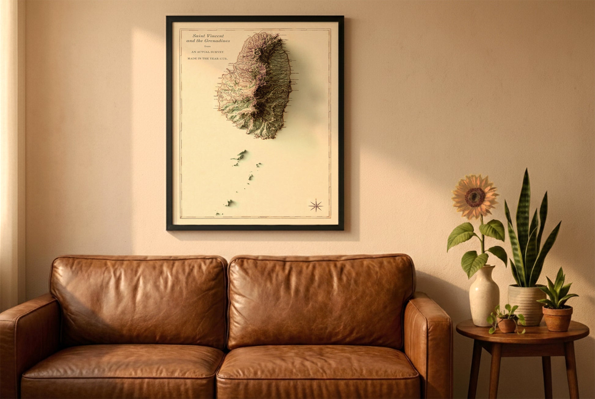 Saint Vincent and the Grenadines vintage relief map in a black frame above a brown leather sofa. Boho living room with warm sunlight, sunflower, and indoor plants on a wooden side table
