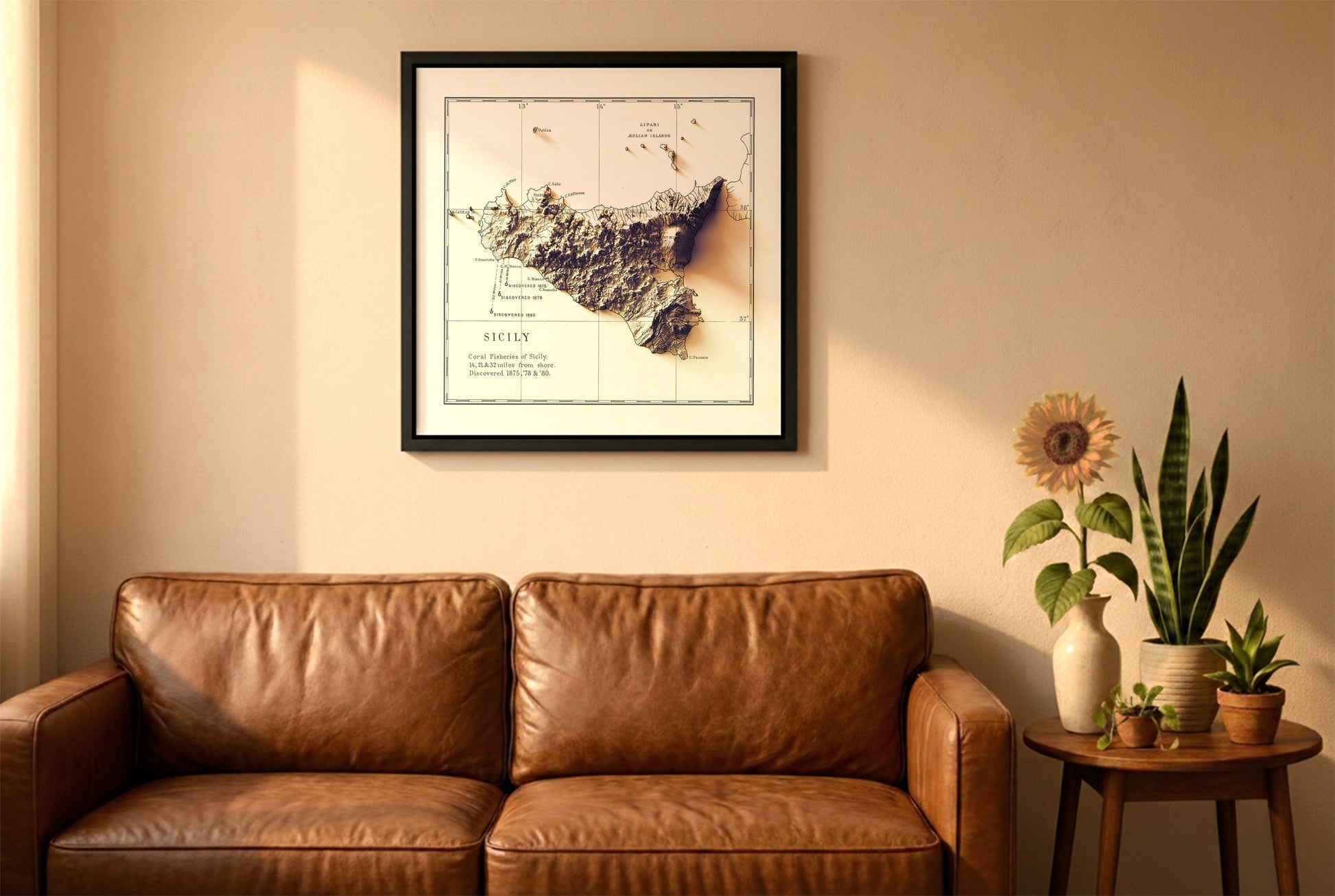 Sicily, Italy, vintage relief map in a black frame above a brown leather sofa. Boho living room with warm sunlight, sunflower, and indoor plants on a wooden side table