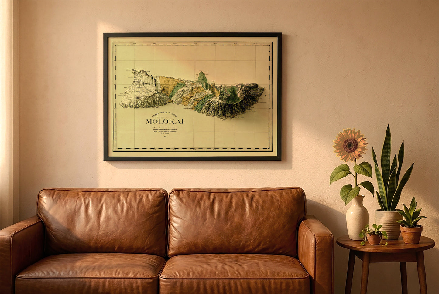 Molokai, Hawaii, vintage relief map in a black frame above a brown leather sofa. Boho living room with warm sunlight, sunflower, and indoor plants on a wooden side table