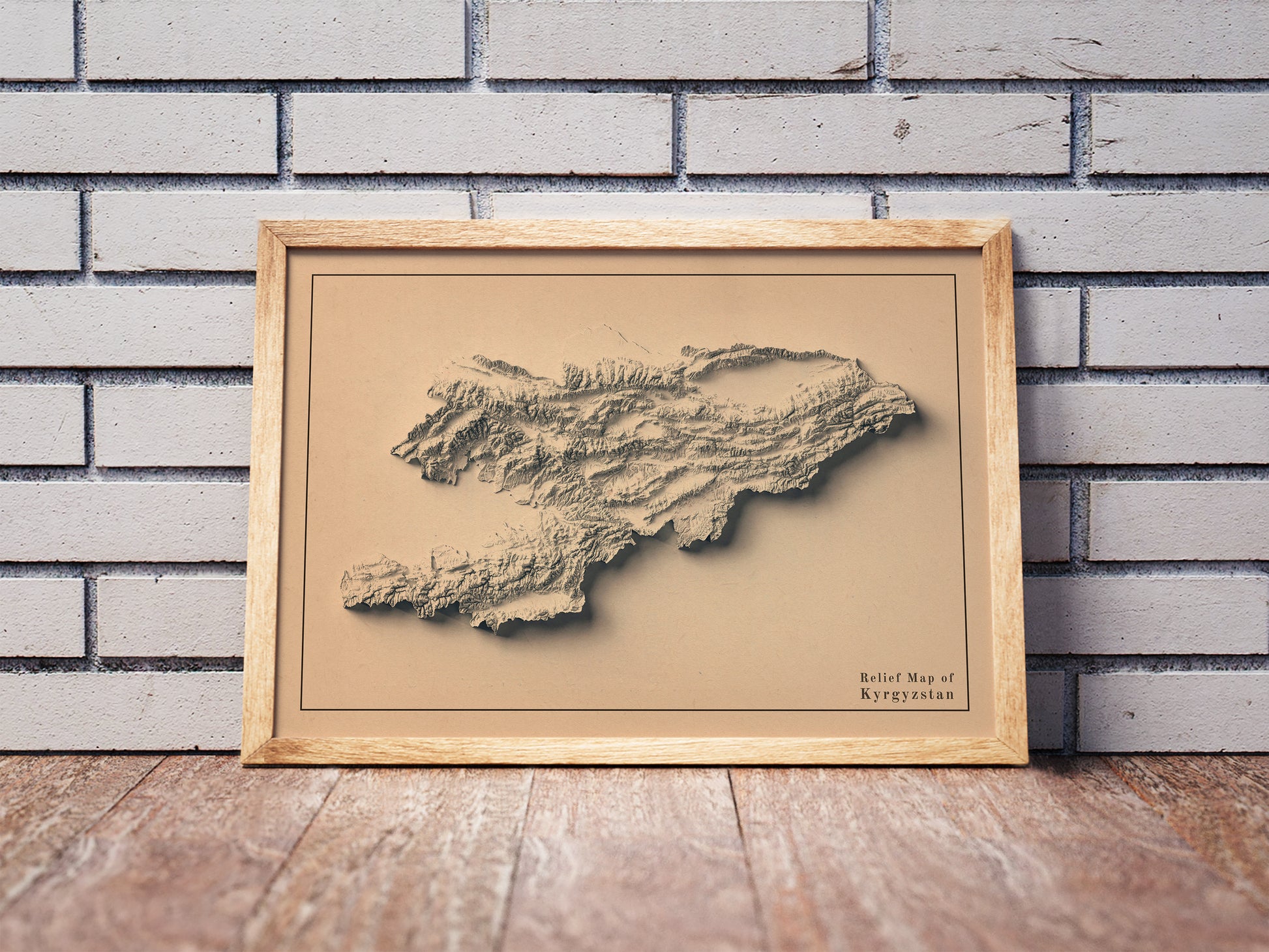 Vintage Kyrgyzstan shaded relief map in a wooden frame. Realistic terrain art print for home decor, displayed against a brick wall