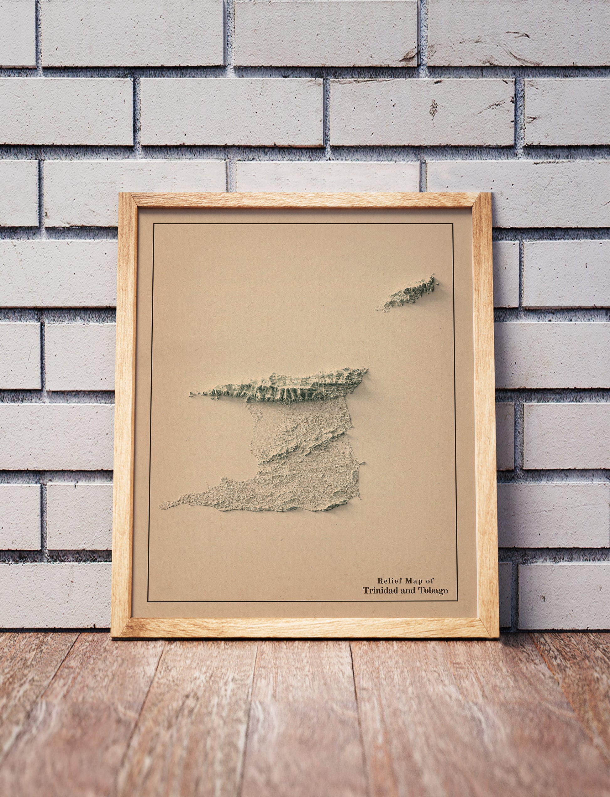 Vintage Trinidad and Tobago shaded relief map in a wooden frame. Realistic terrain art print for home decor, displayed against a brick wall