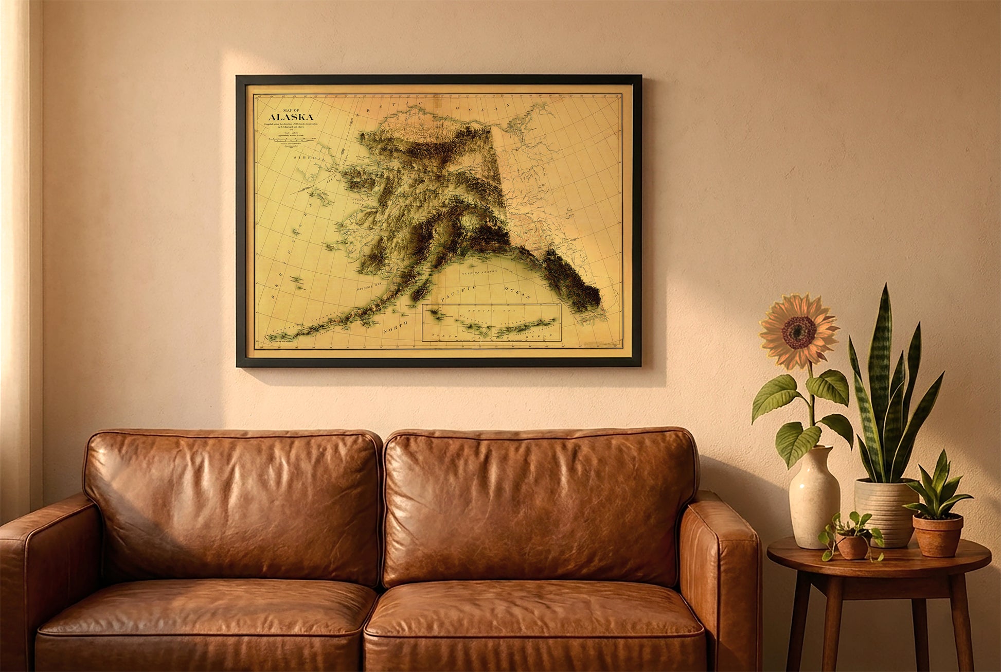 Alaska vintage relief map in a black frame above a brown leather sofa. Boho living room with warm sunlight, sunflower, and indoor plants on a wooden side table