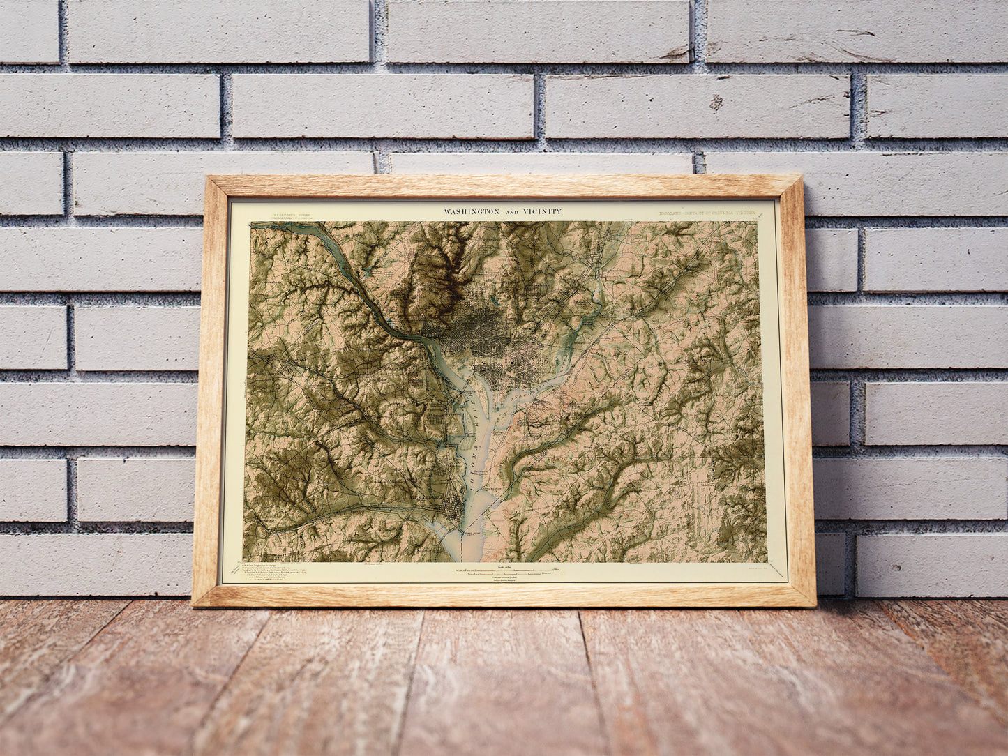 Vintage Washington DC shaded relief map in a wooden frame. Realistic terrain art print for home decor, displayed against a brick wall