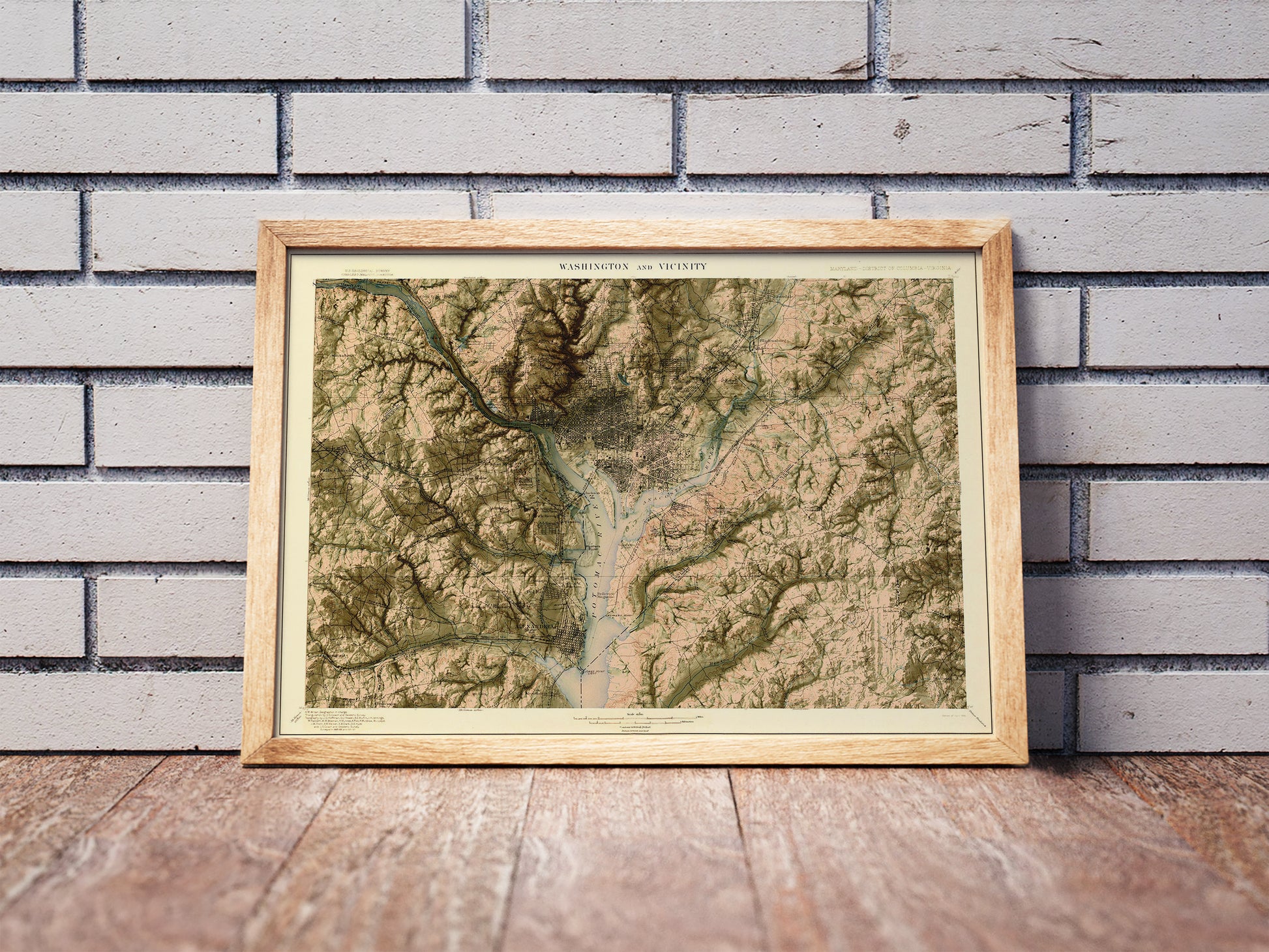 Vintage Washington DC shaded relief map in a wooden frame. Realistic terrain art print for home decor, displayed against a brick wall