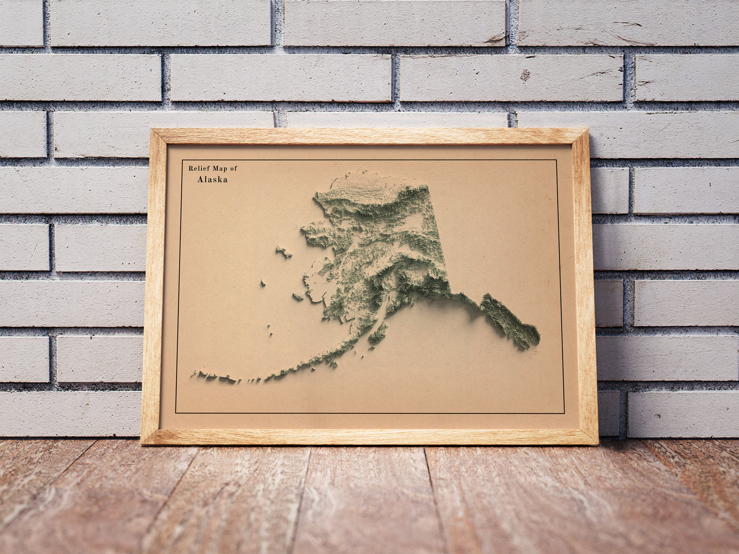 Vintage Alaska shaded relief map in a wooden frame. Realistic terrain art print for home decor, displayed against a brick wall