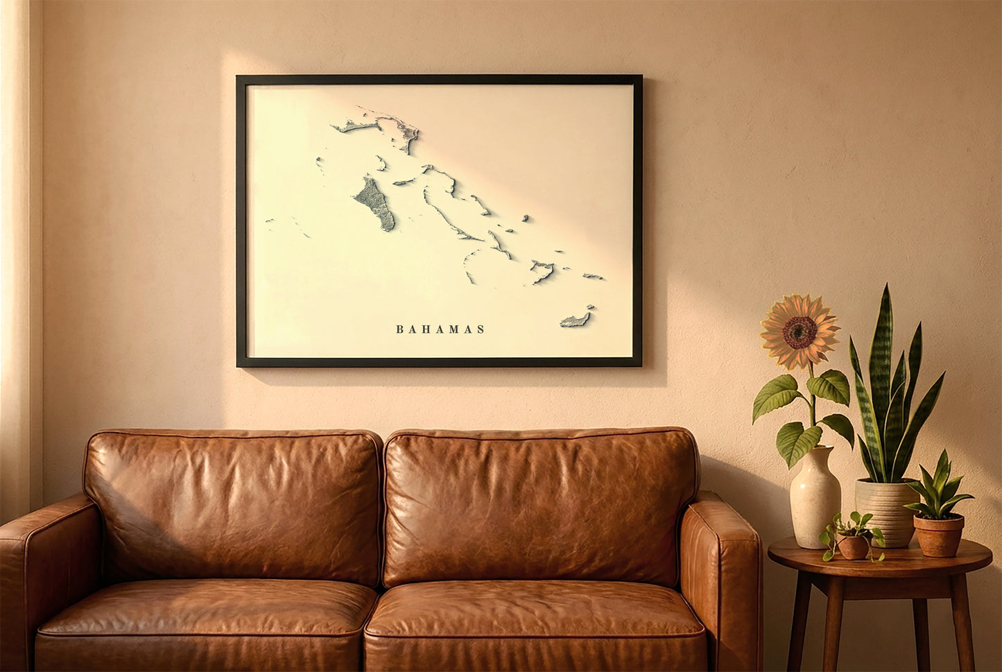 Bahamas relief map in a black frame above a brown leather sofa. Boho living room with warm sunlight, sunflower, and indoor plants on a wooden side table