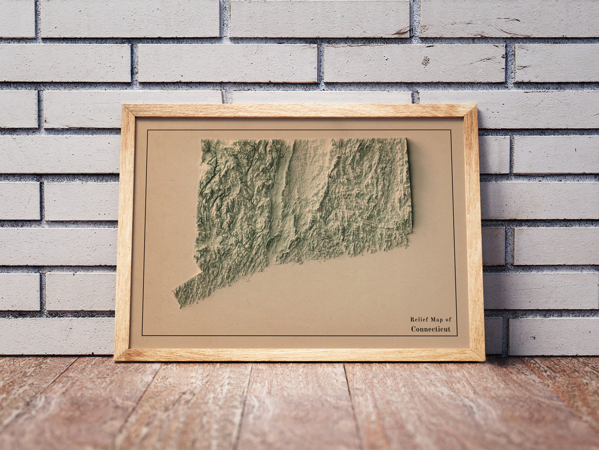 Vintage Connecticut shaded relief map in a wooden frame. Realistic terrain art print for home decor, displayed against a brick wall