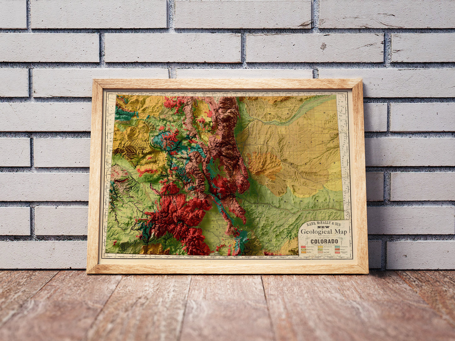 Vintage Colorado shaded relief map in a wooden frame. Realistic terrain art print for home decor, displayed against a brick wall