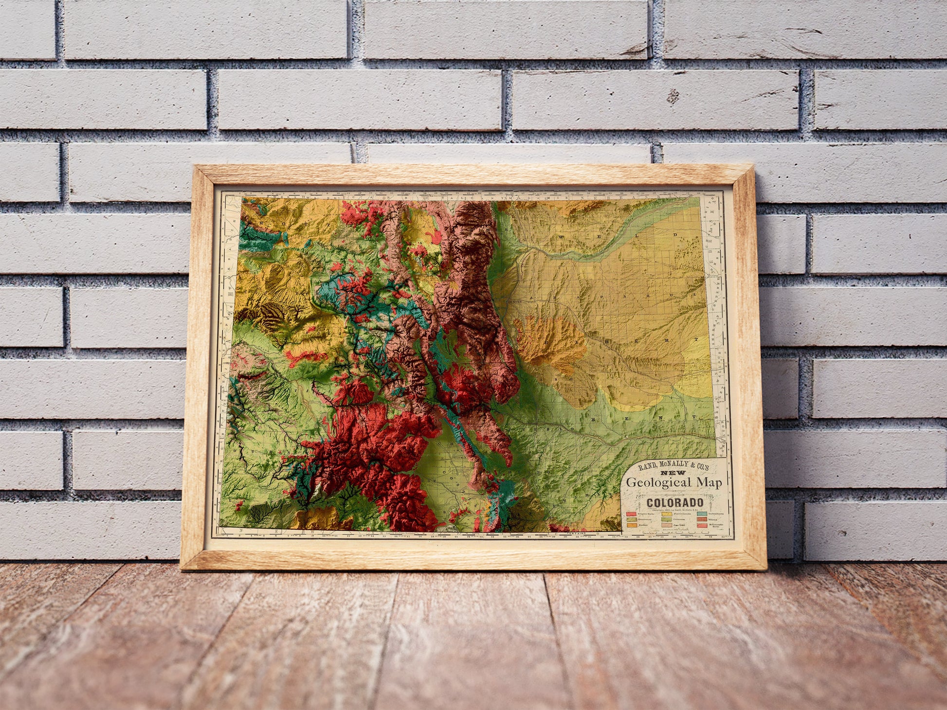 Vintage Colorado shaded relief map in a wooden frame. Realistic terrain art print for home decor, displayed against a brick wall