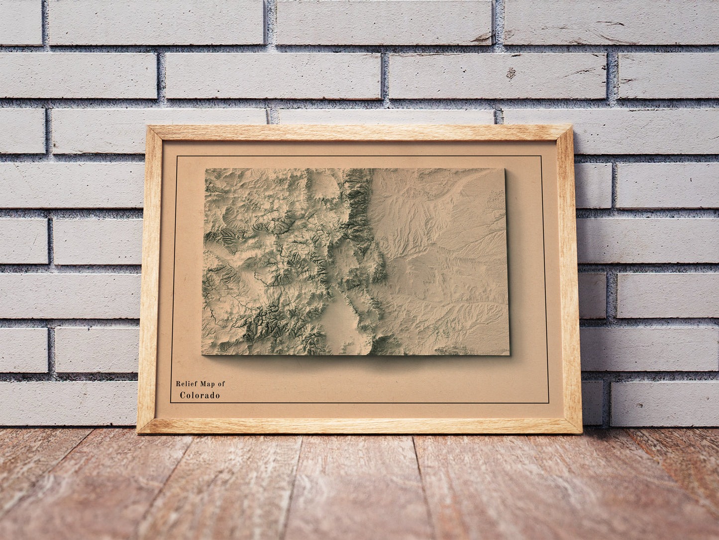 Vintage Colorado shaded relief map in a wooden frame. Realistic terrain art print for home decor, displayed against a brick wall