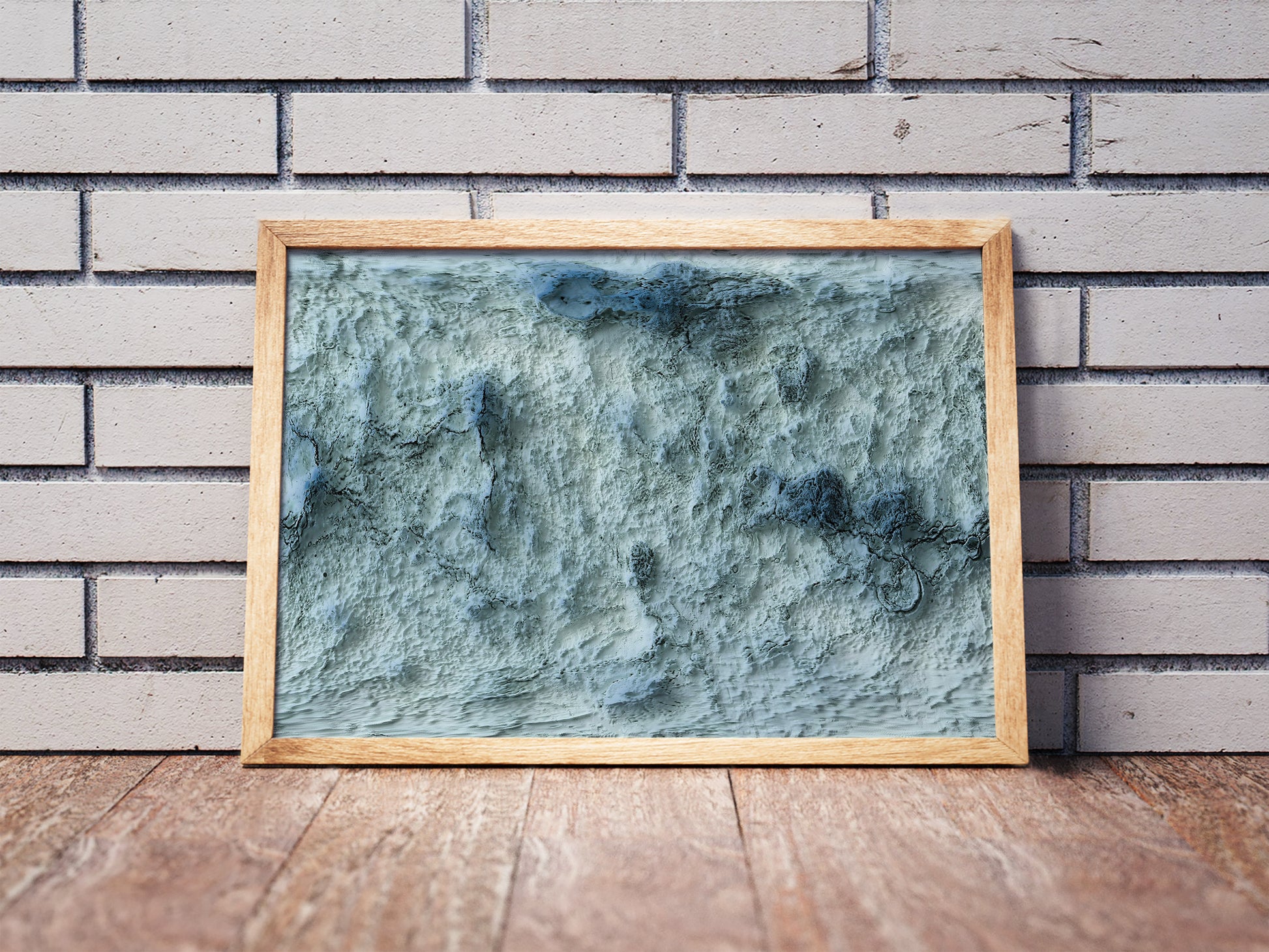 Venus shaded relief map in a wooden frame. Realistic terrain art print for home decor, displayed against a brick wall