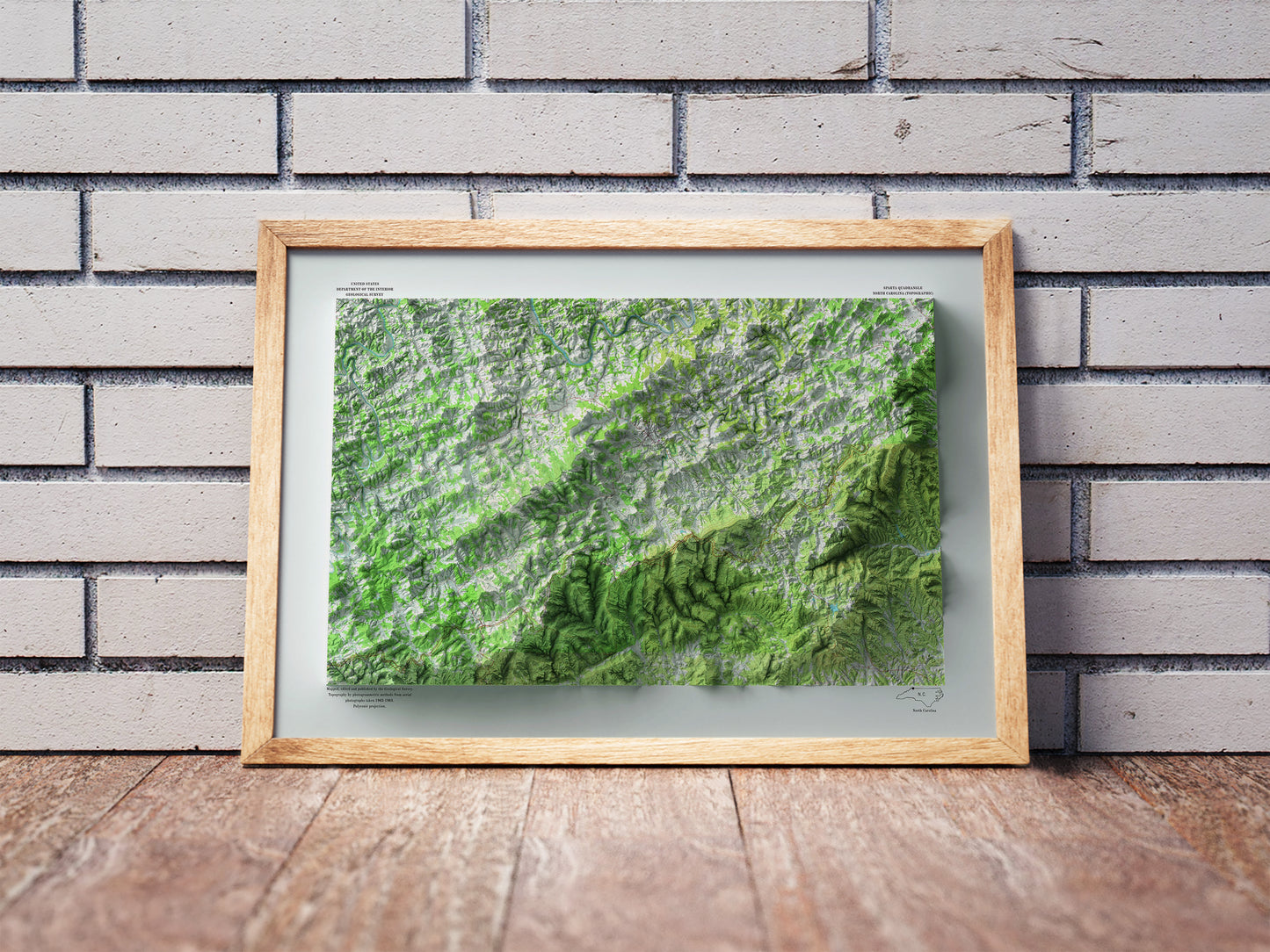 Vintage Alleghany County shaded relief map in a wooden frame. Realistic terrain art print for home decor, displayed against a brick wall