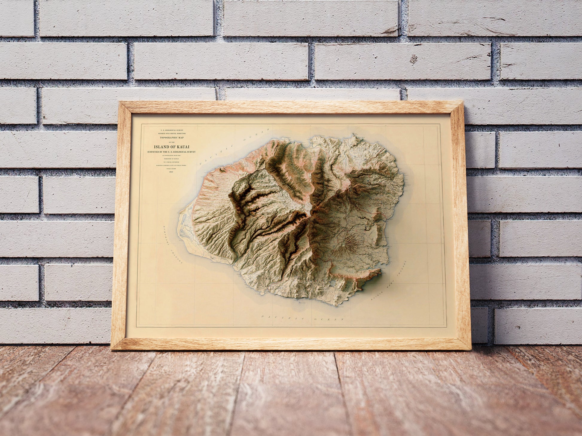 Vintage Kauai, Hawaii, shaded relief map in a wooden frame. Realistic terrain art print for home decor, displayed against a brick wall