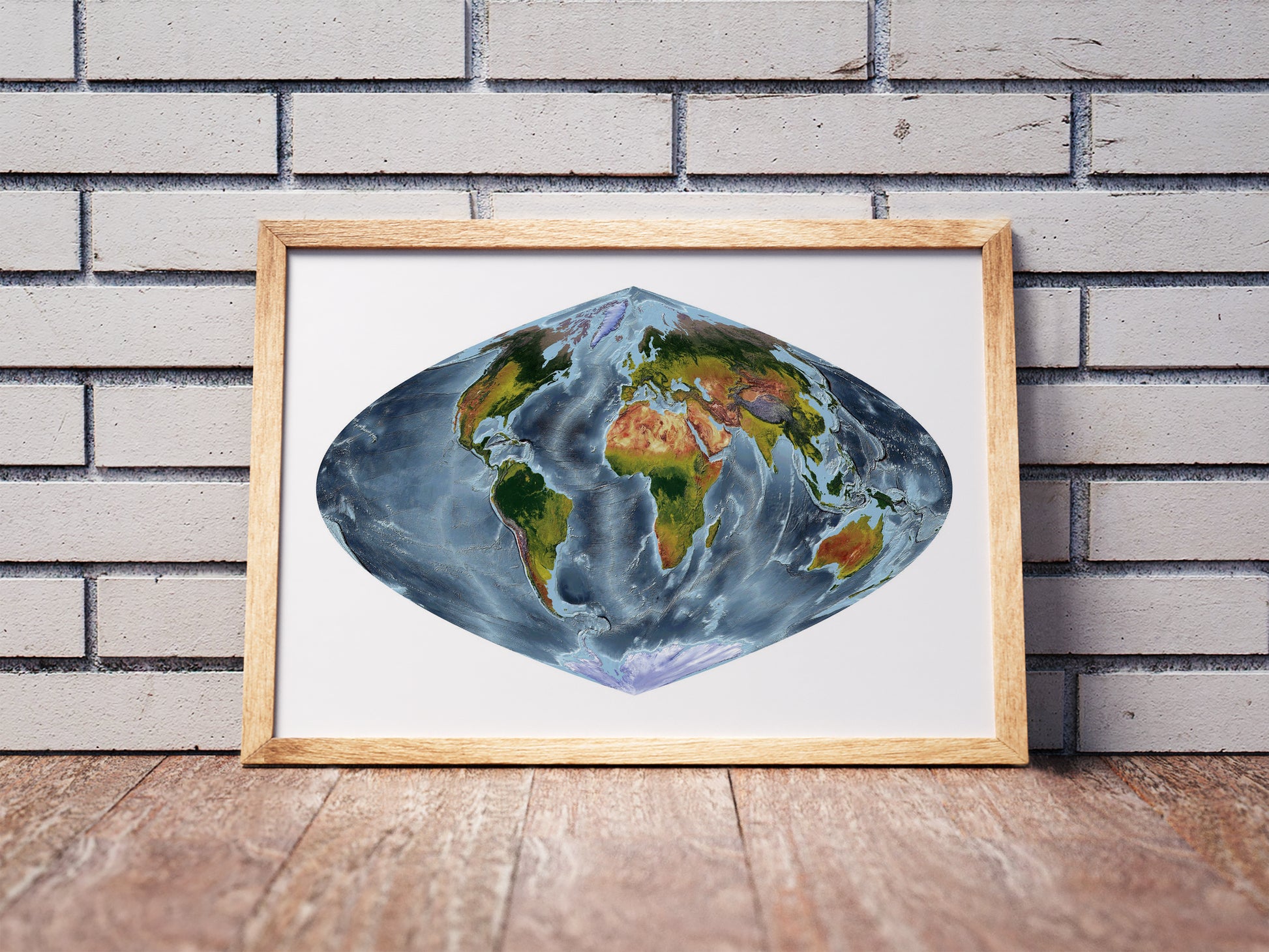 Craster Parabolic projection shaded relief world map in a wooden frame. Realistic terrain art print for home decor, displayed against a brick wall