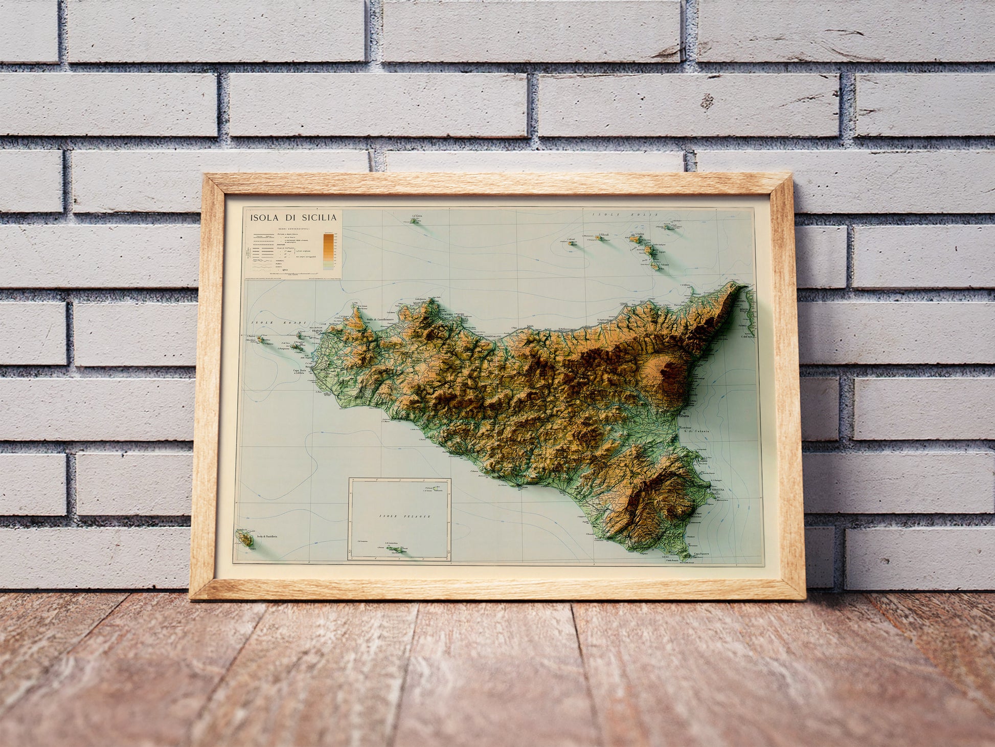 Vintage Sicily, Italy, shaded relief map in a wooden frame. Realistic terrain art print for home decor, displayed against a brick wall