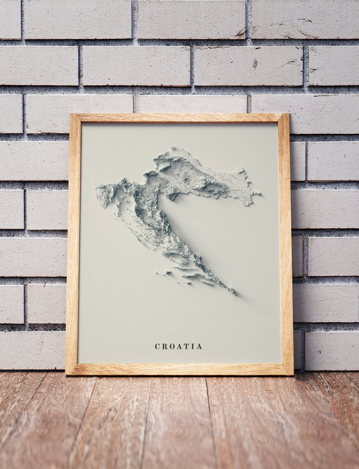Croatia shaded relief map in a wooden frame. Realistic terrain art print for home decor, displayed against a brick wall