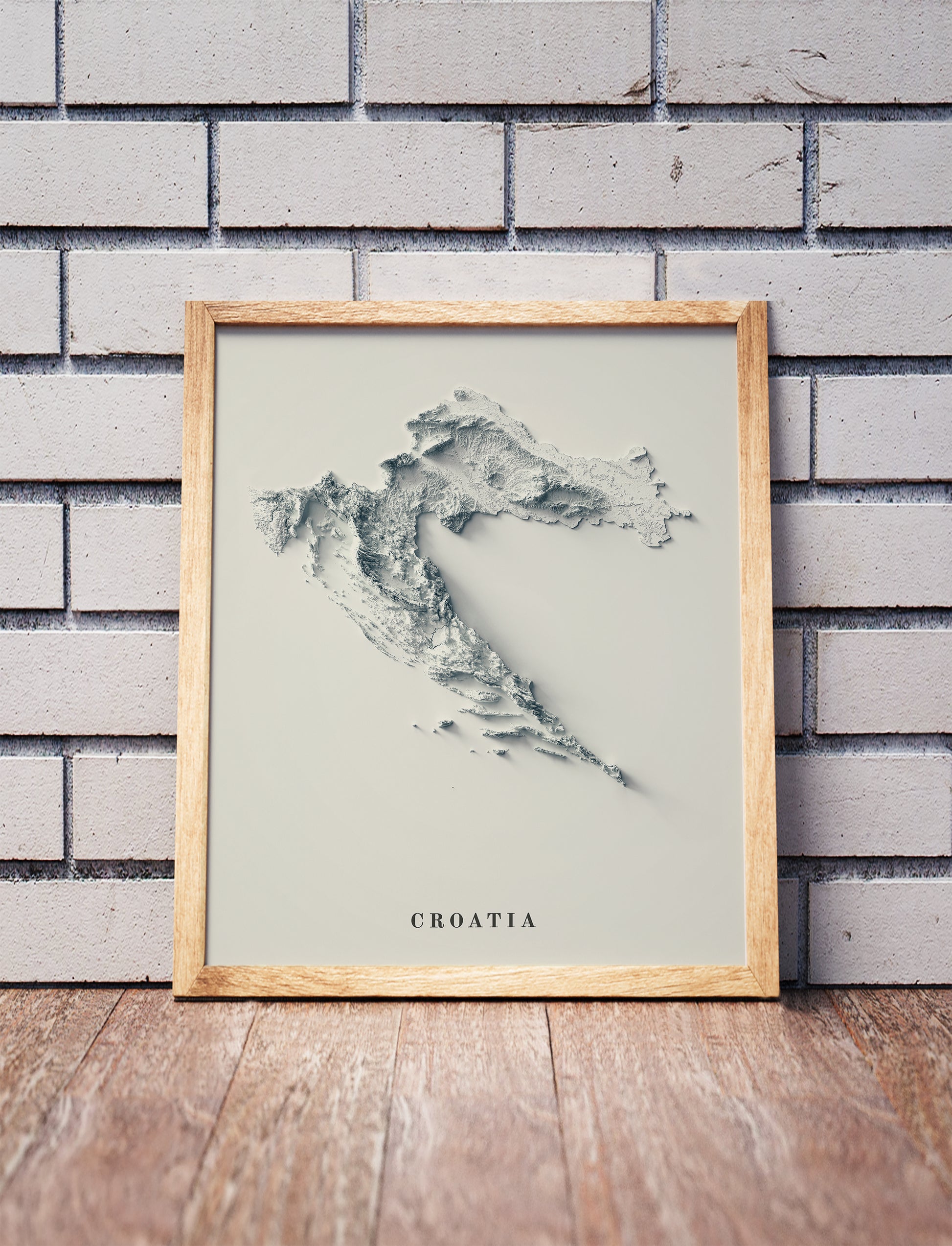 Croatia shaded relief map in a wooden frame. Realistic terrain art print for home decor, displayed against a brick wall