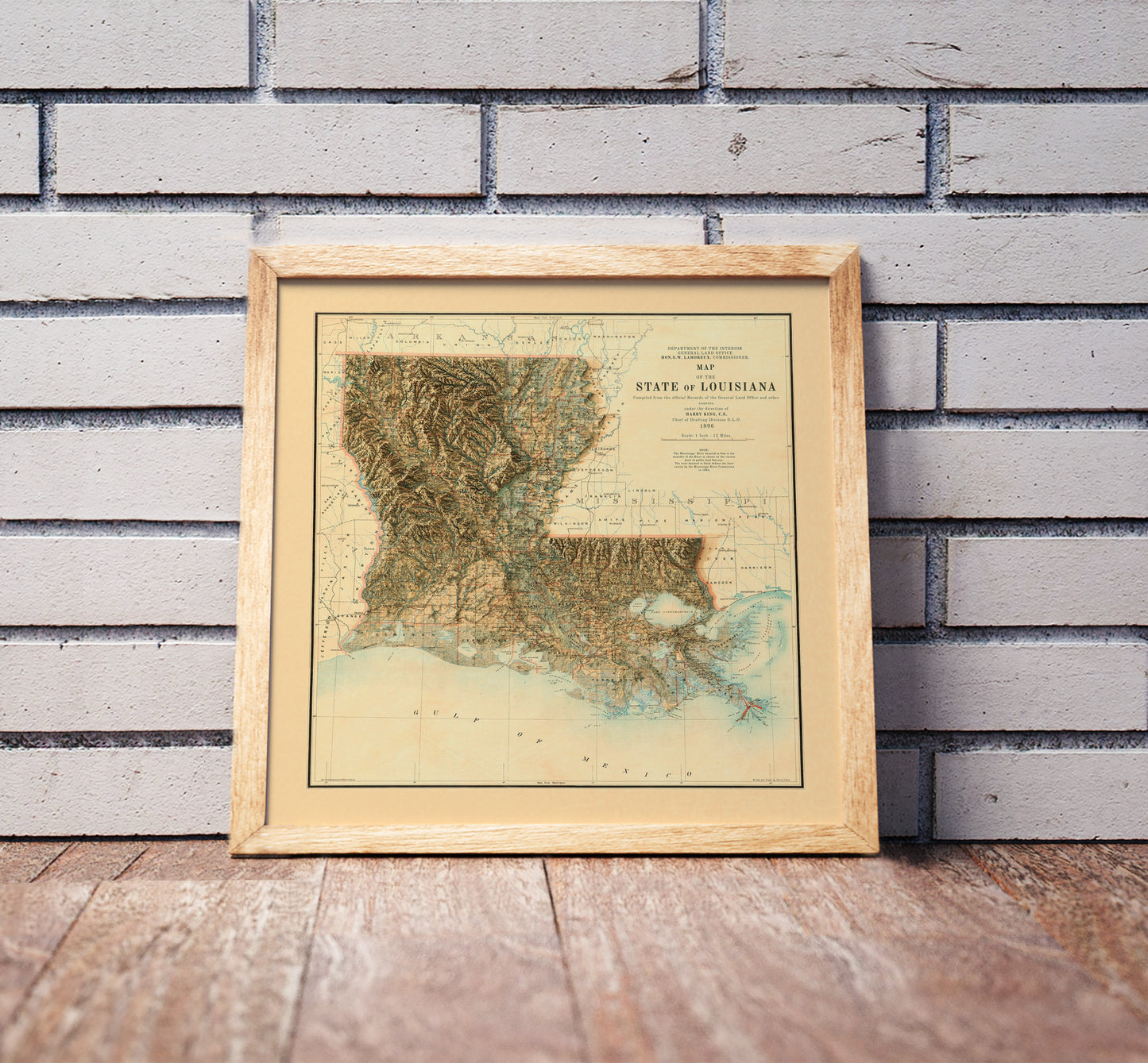 Vintage Louisiana shaded relief map in a wooden frame. Realistic terrain art print for home decor, displayed against a brick wall