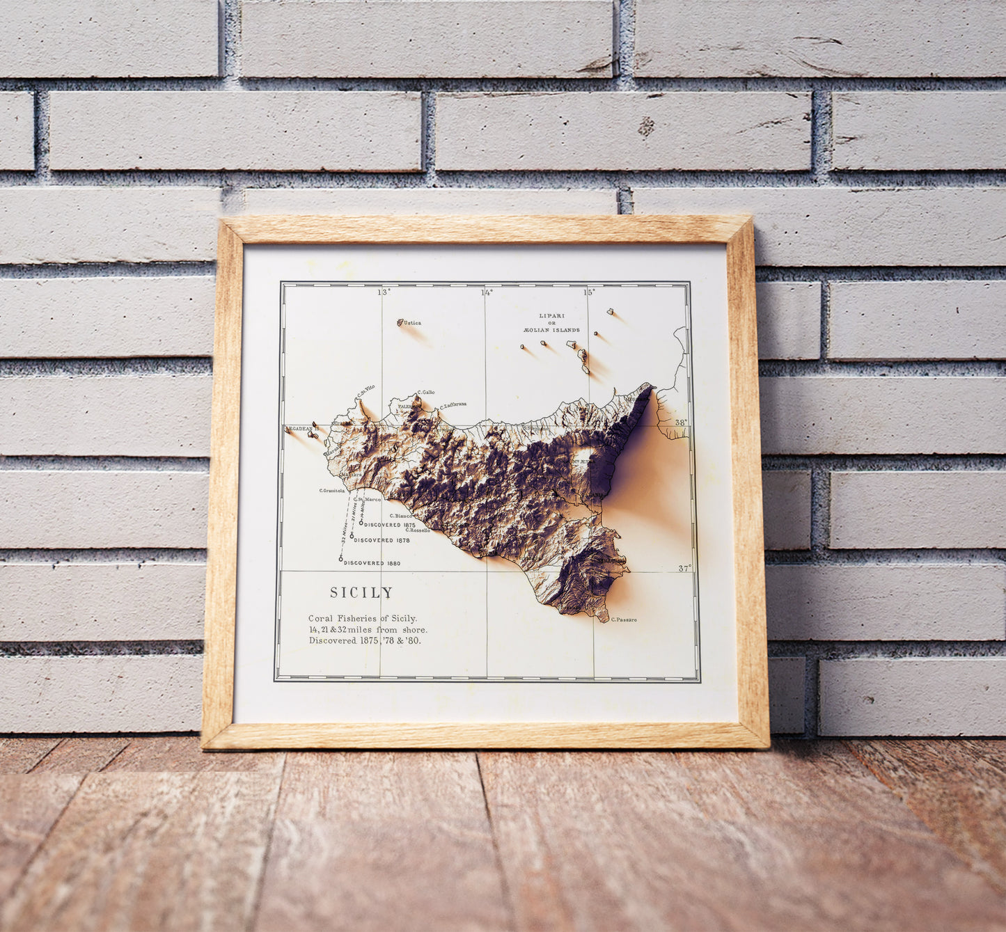 Vintage Sicily, Italy, shaded relief map in a wooden frame. Realistic terrain art print for home decor, displayed against a brick wall