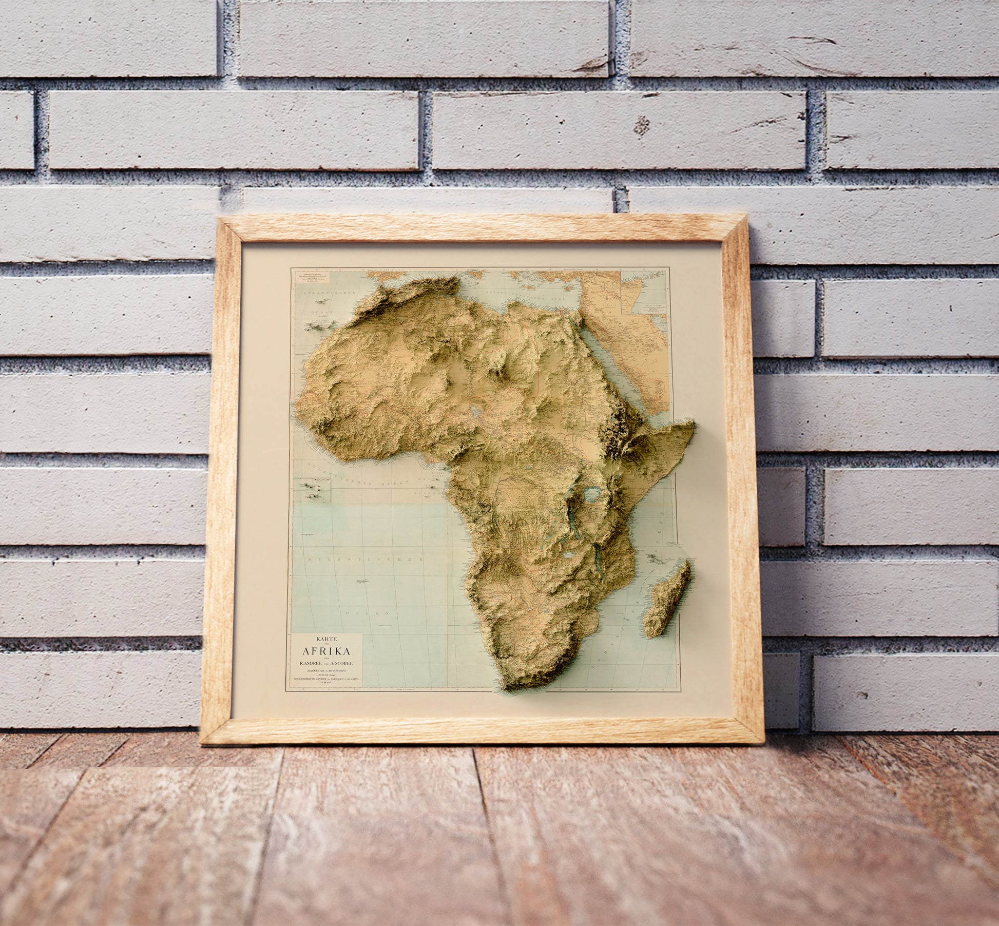 Vintage Africa shaded relief map in a wooden frame. Realistic terrain art print for home decor, displayed against a brick wall