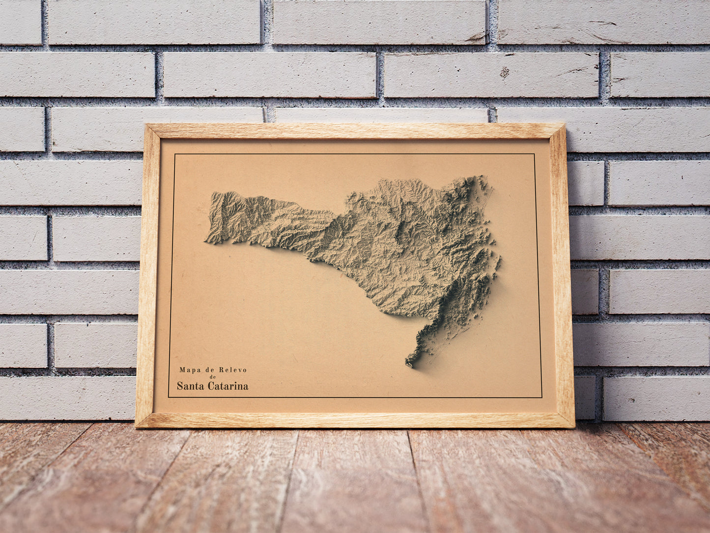Vintage Santa Catarina shaded relief map in a wooden frame. Realistic terrain art print for home decor, displayed against a brick wall