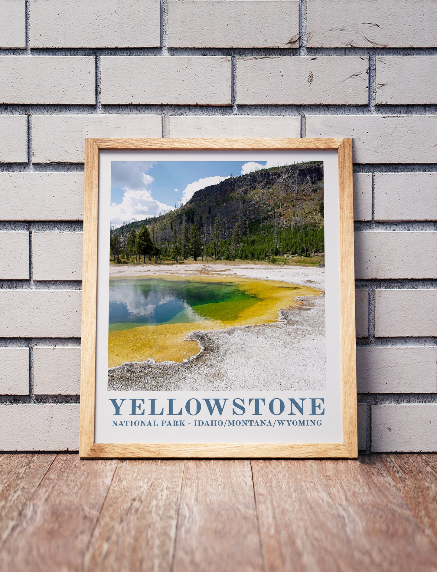 Yellowstone poster in a wooden frame. Realistic terrain art print for home decor, displayed against a brick wall