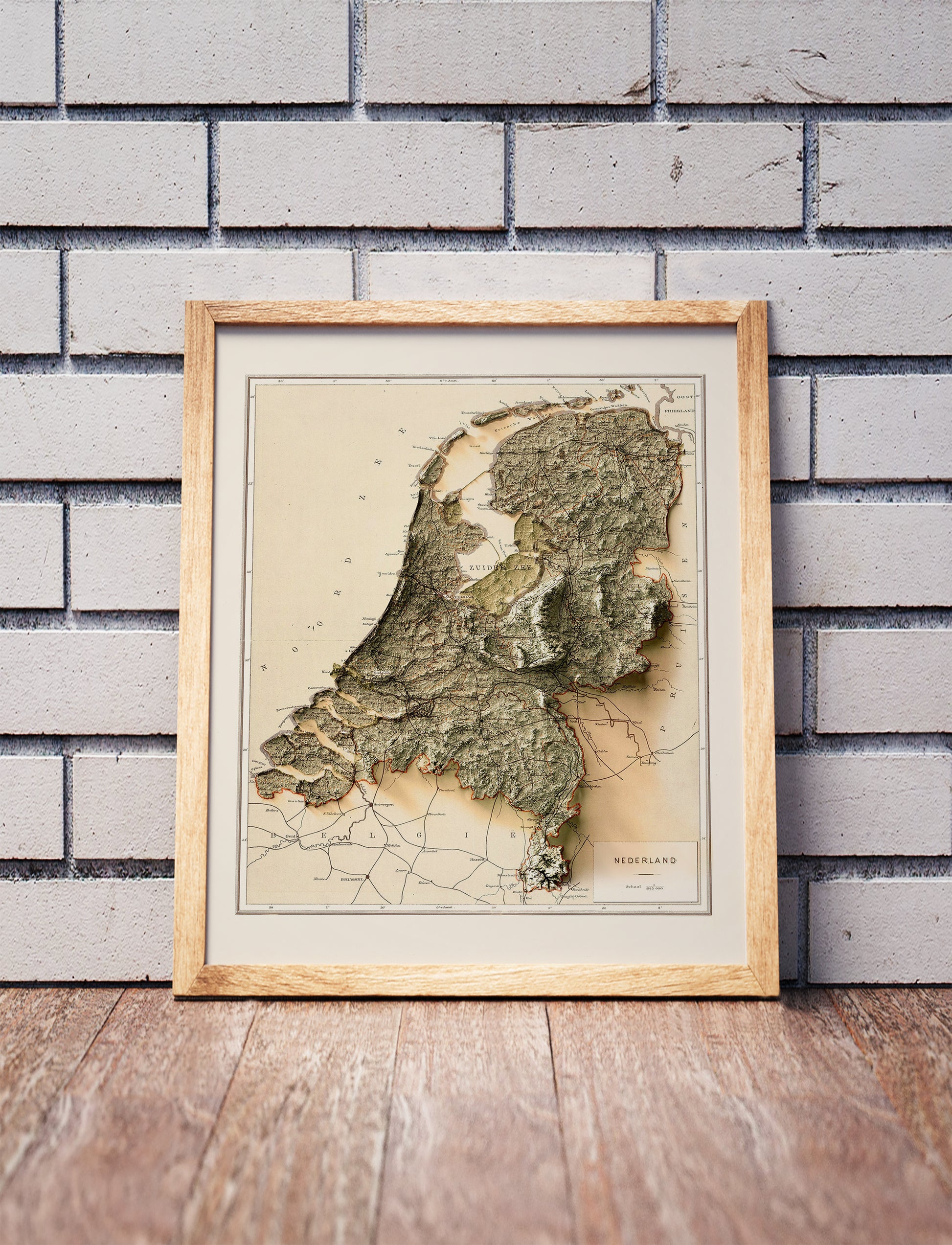 Vintage Netherlands shaded relief map in a wooden frame. Realistic terrain art print for home decor, displayed against a brick wall