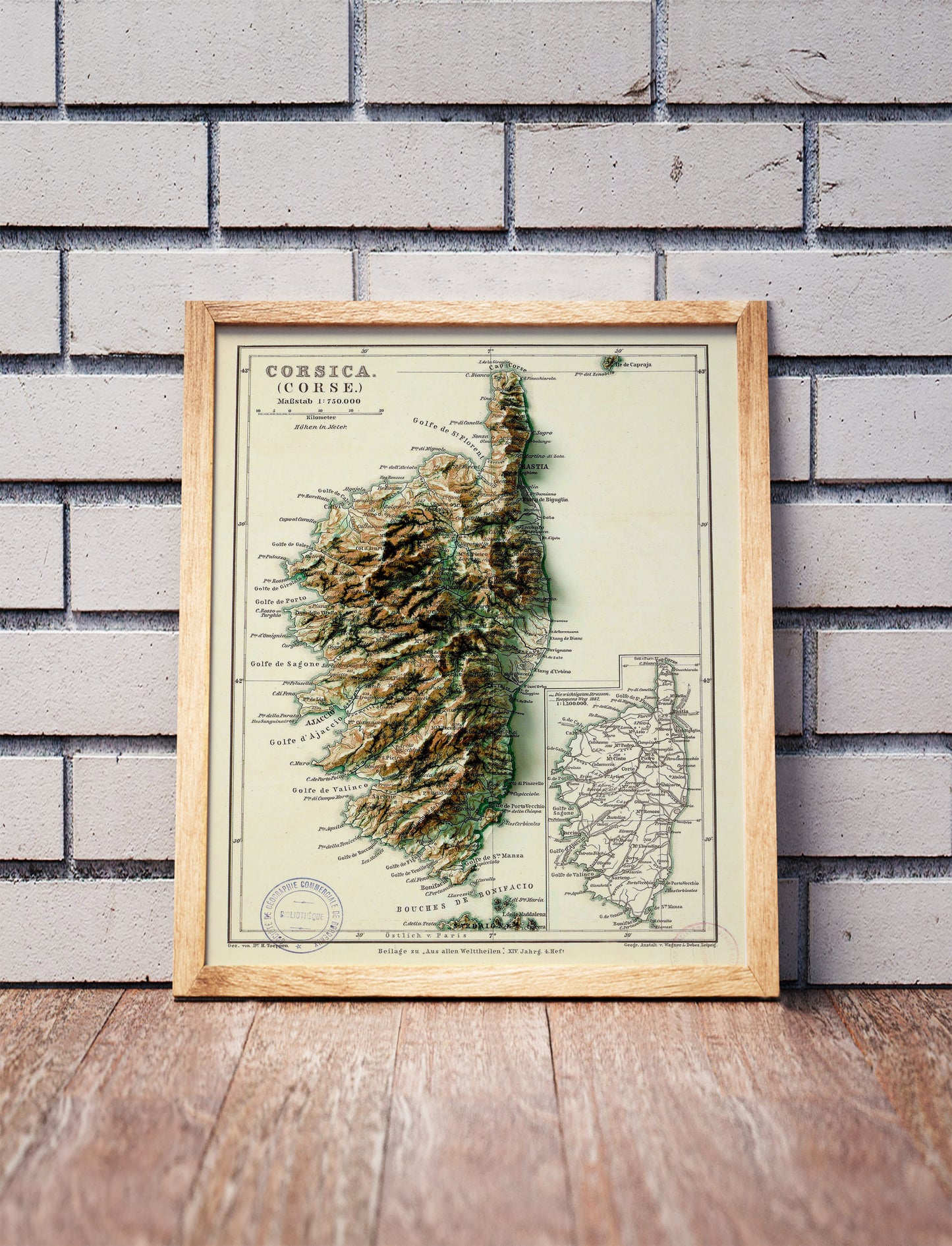 Vintage Corsica Corse shaded relief map in a wooden frame. Realistic terrain art print for home decor, displayed against a brick wall
