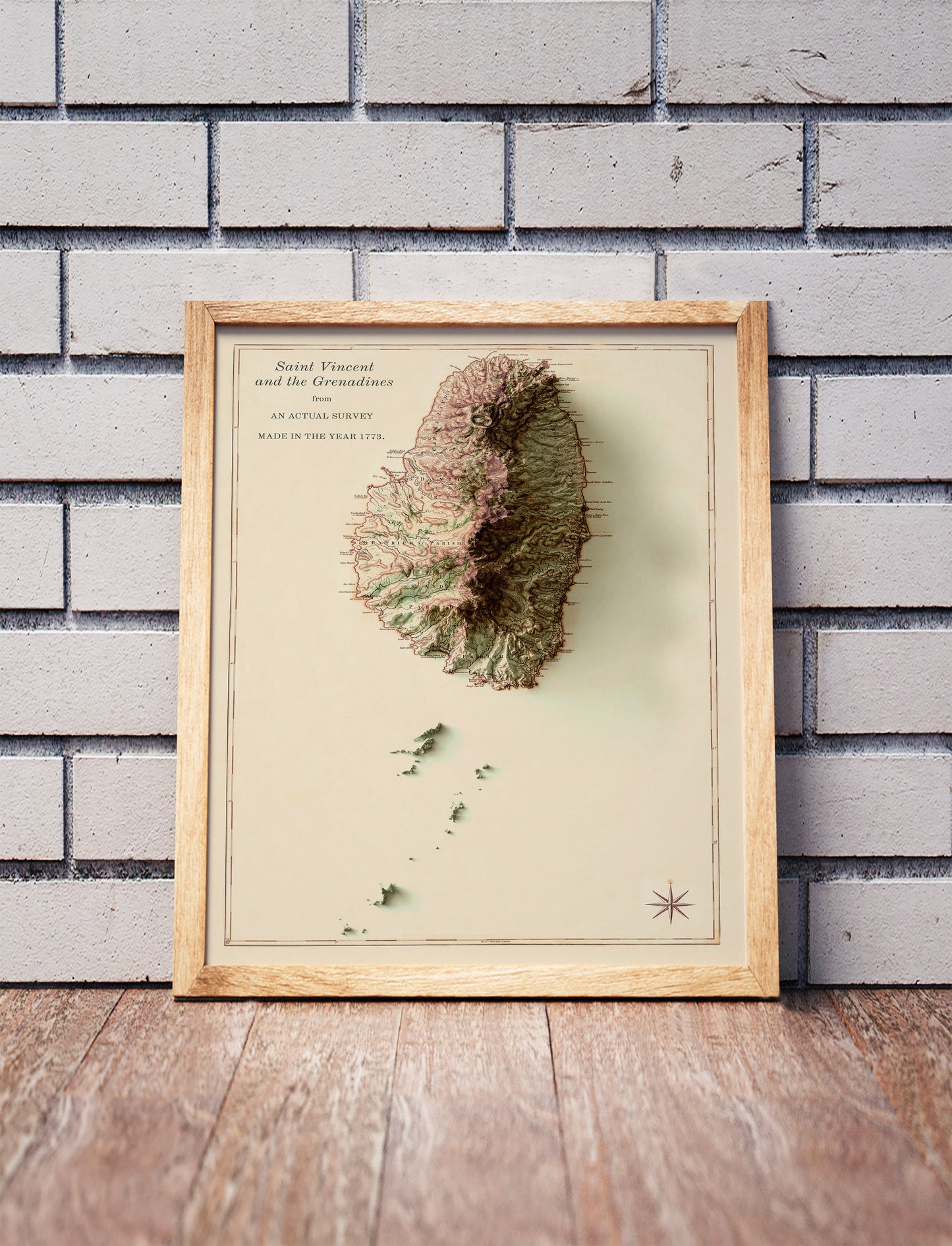 Vintage Saint Vincent and the Grenadines shaded relief map in a wooden frame. Realistic terrain art print for home decor, displayed against a brick wall