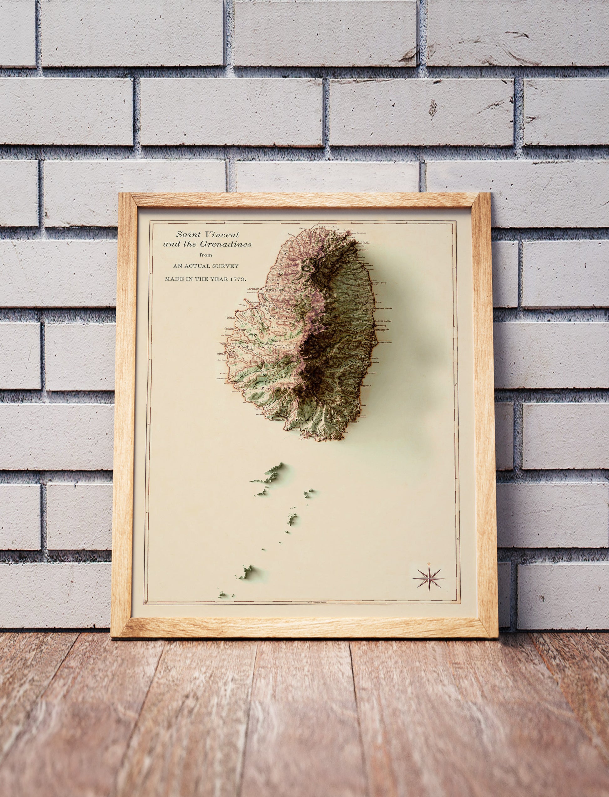 Vintage Saint Vincent and the Grenadines shaded relief map in a wooden frame. Realistic terrain art print for home decor, displayed against a brick wall