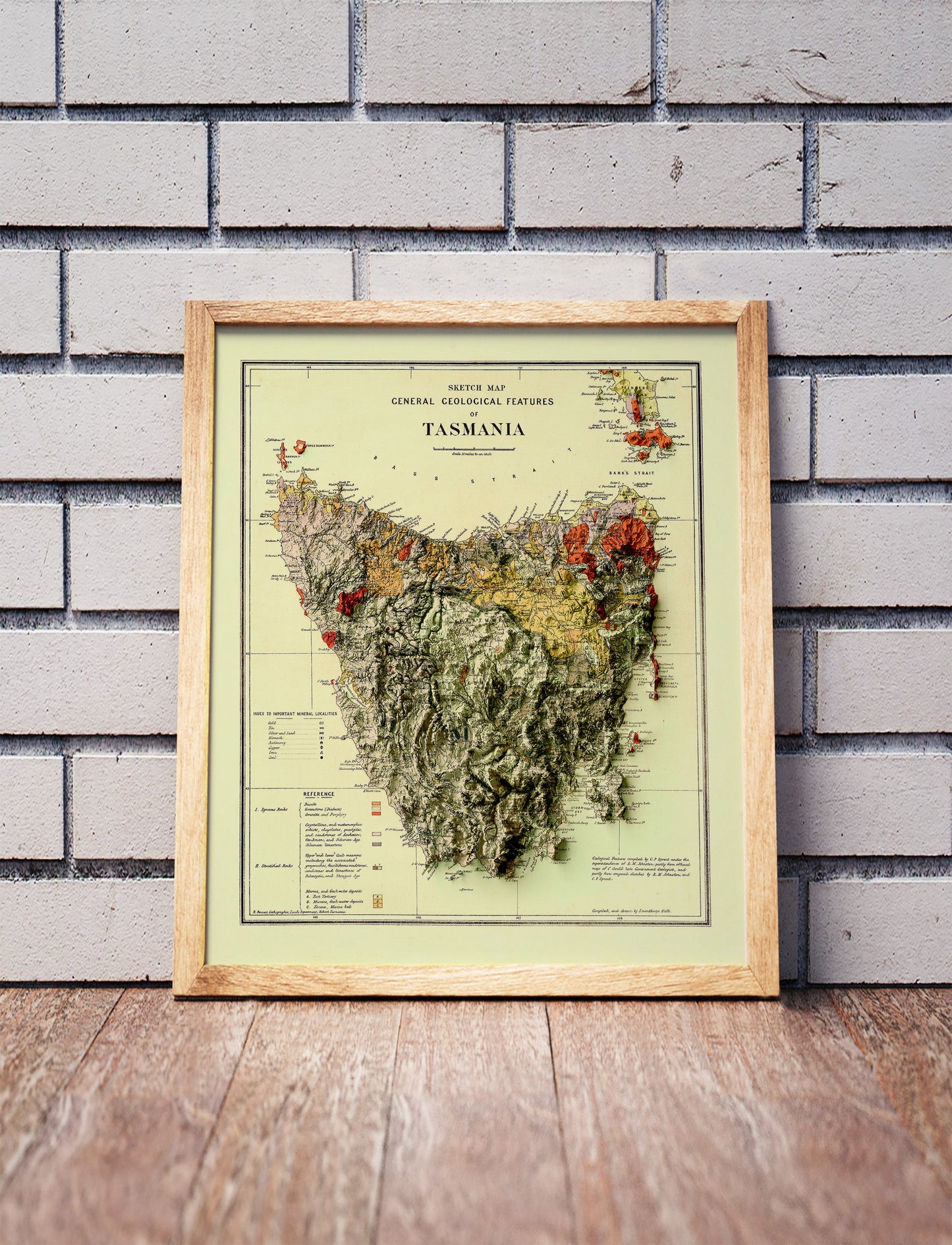 Vintage Tasmania, Australia, shaded relief map in a wooden frame. Realistic terrain art print for home decor, displayed against a brick wall