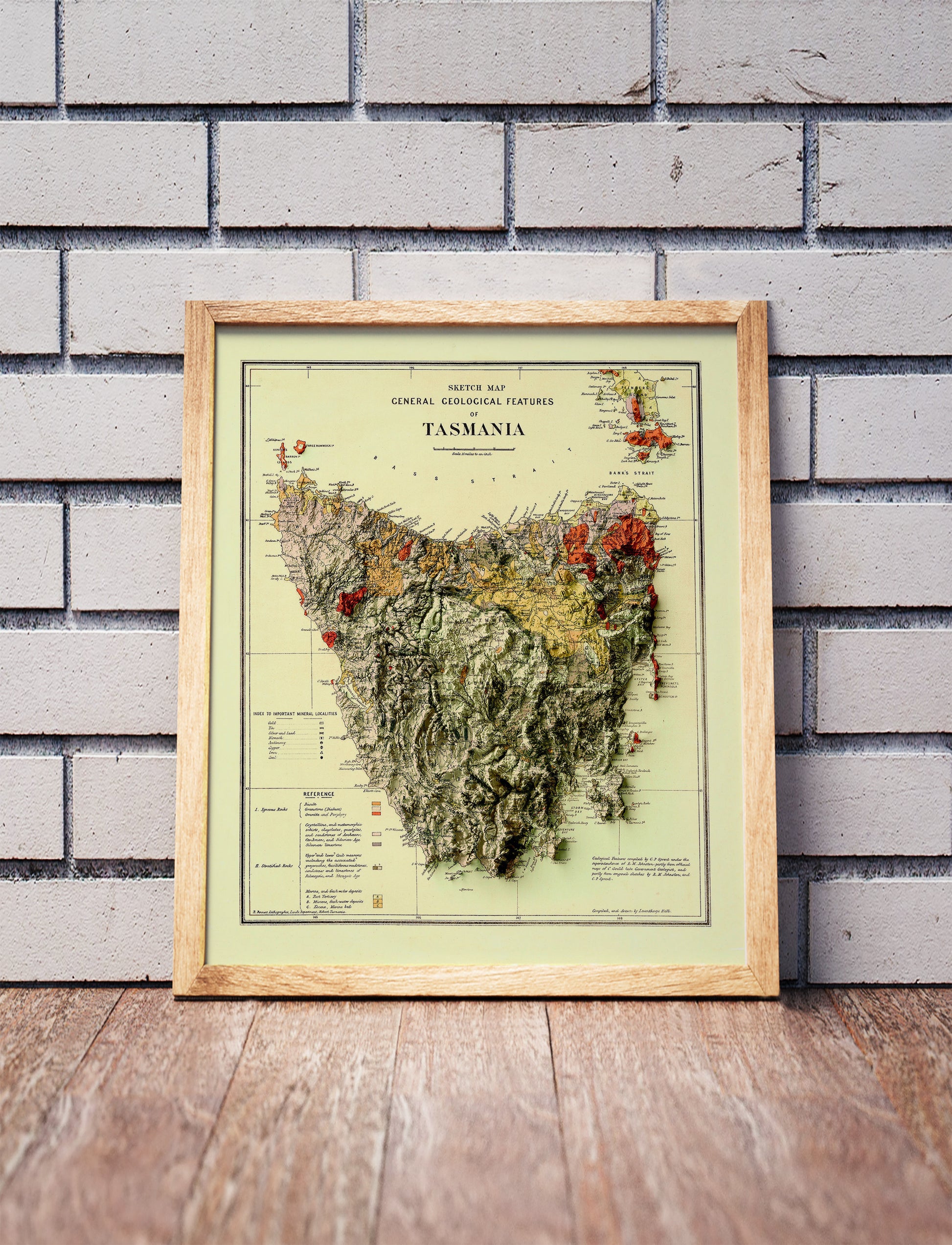 Vintage Tasmania, Australia, shaded relief map in a wooden frame. Realistic terrain art print for home decor, displayed against a brick wall